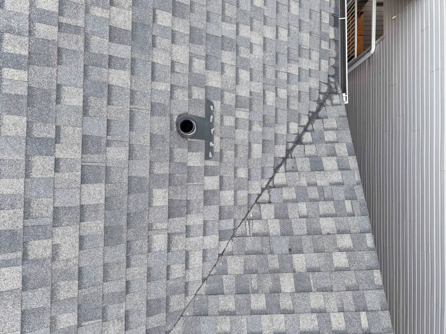 Close aerial detail of roof shingles, a vent and valley